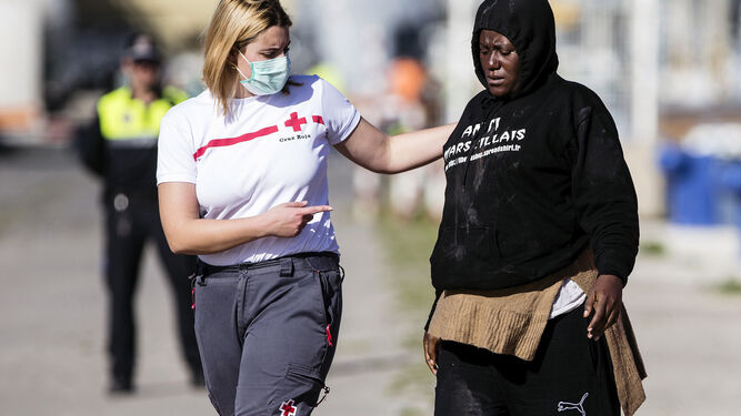 Una voluntaria de la Cruz Roja atiende en el puerto de Málaga a una inmigrante que fue rescatada ayer de una patera cerca de la isla de Alborán.
