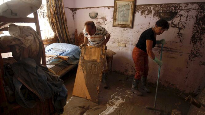 Varias personas limpian el lodo acumulado en el interior de una vivienda de Garrucha.