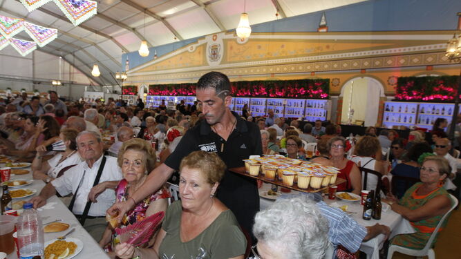 Un camarero dando los postres en la comida en homenaje a los mayores en el Ferial de Almería, donde han asistido unas mil personas.