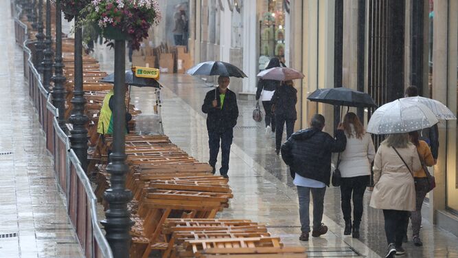 Viandantes con paraguas atraviesan la calle Larios esta Semana Santa.