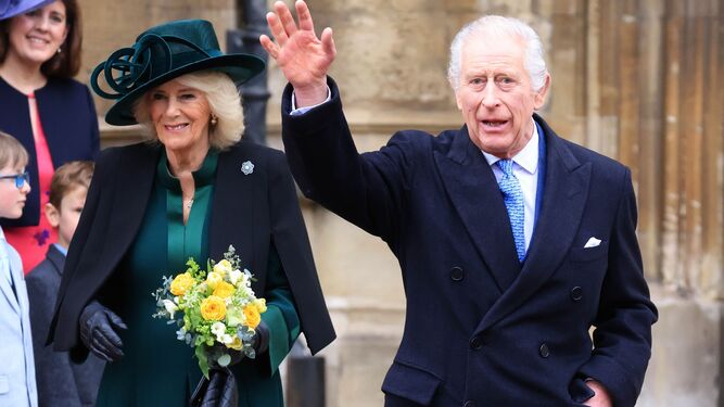 Carlos III, acompañado por la reina Camila, saluda a su salida de misa en la iglesia de San Jorge del castillo de Windsor.